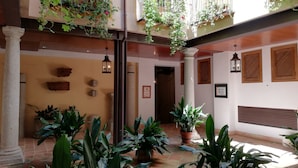 Une cour avec des plantes en pot, un sol carrelé et un banc en bois.