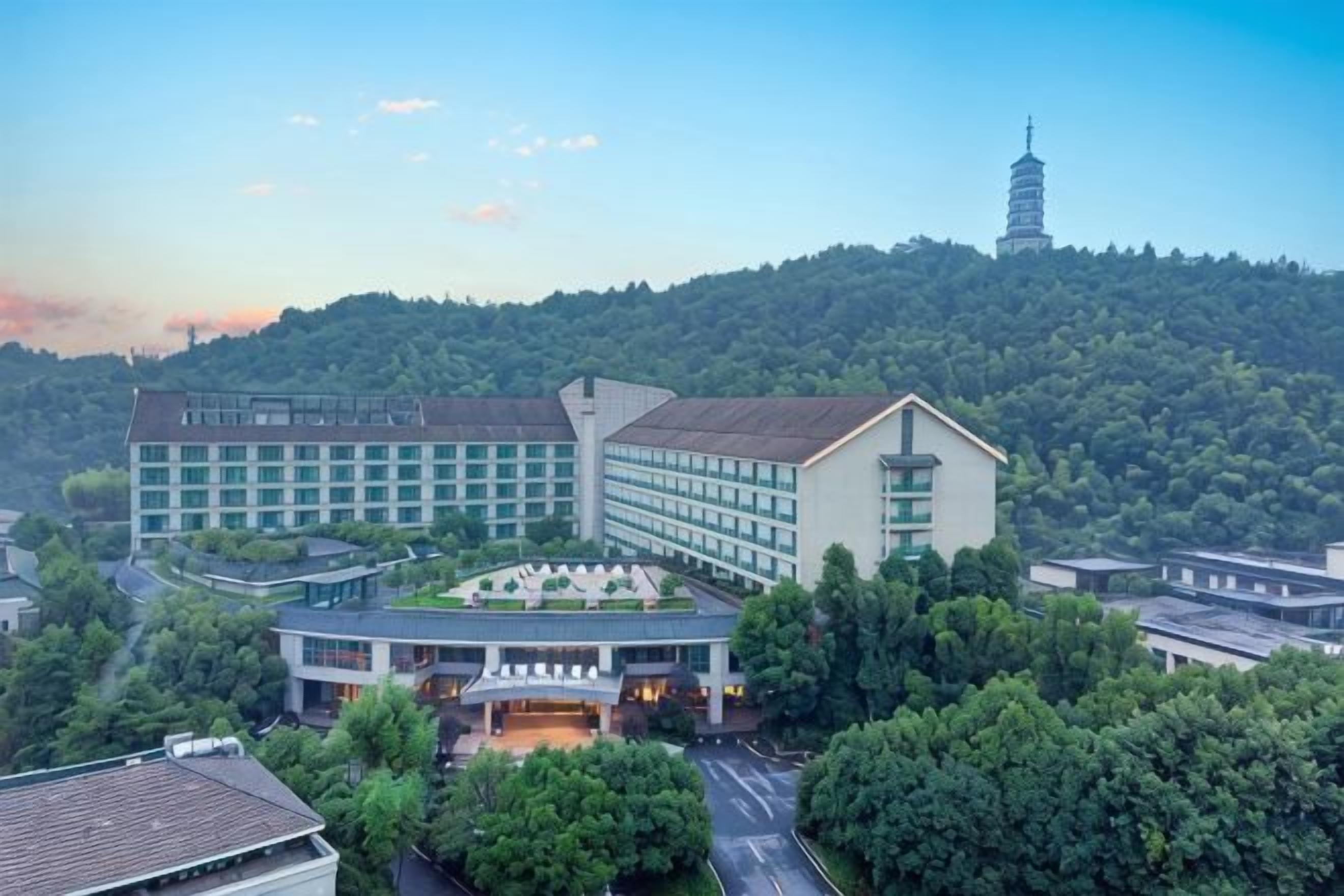 Ein Hotelkomplex mit mehreren Gebäuden, einer Pagode und üppiger Bepflanzung im Hintergrund.