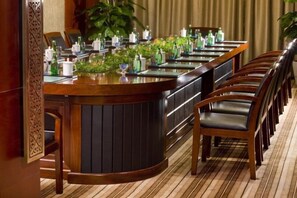 A long dining table with chairs, surrounded by potted plants and bottles. - Taixuhu Holiday Hotel (Hangzhou)