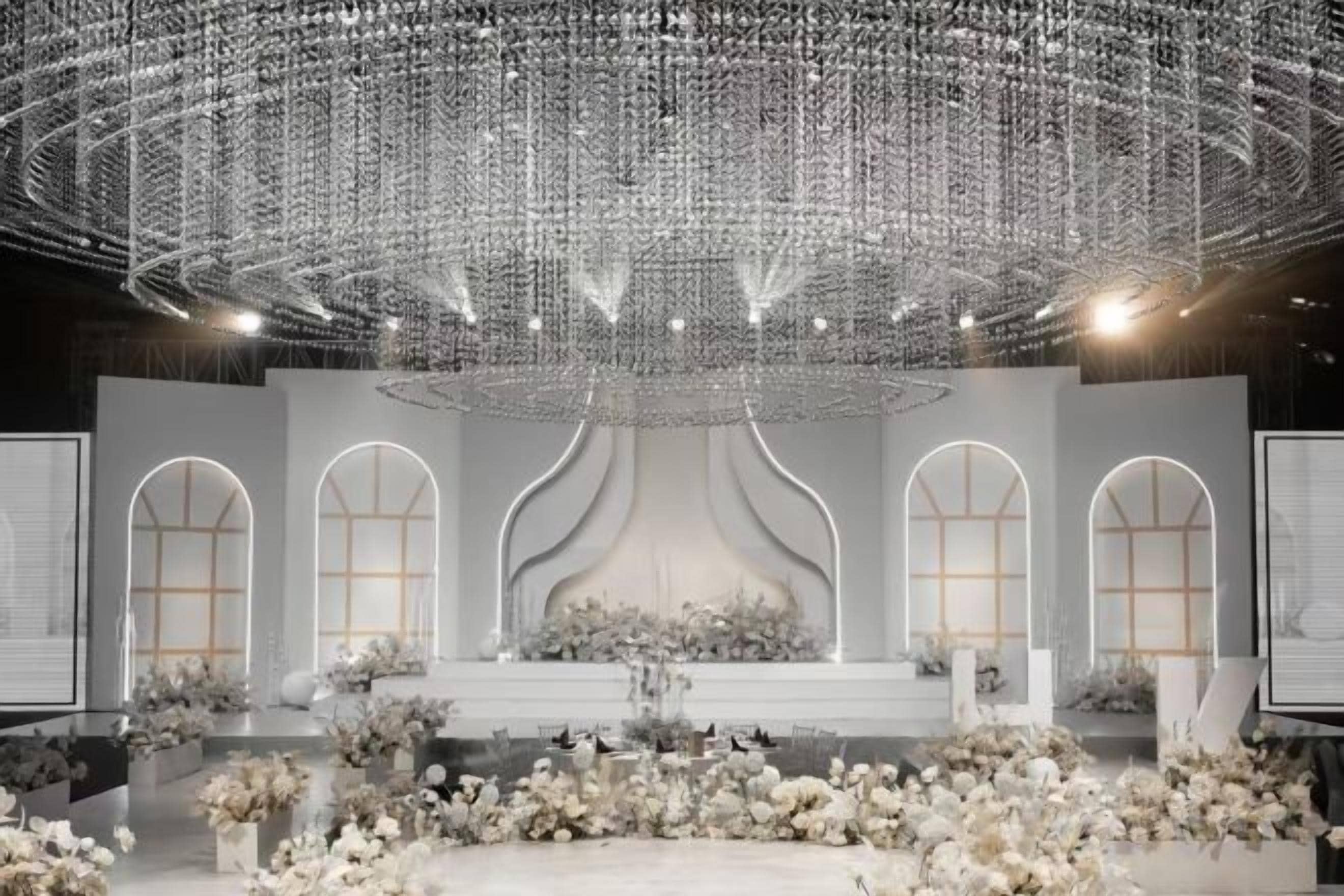 An indoor venue with a stage, arched windows, and a decorative ceiling.