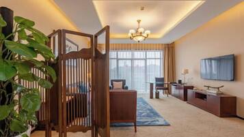 A hotel room with a large window, a chandelier, a TV, and a wooden partition.