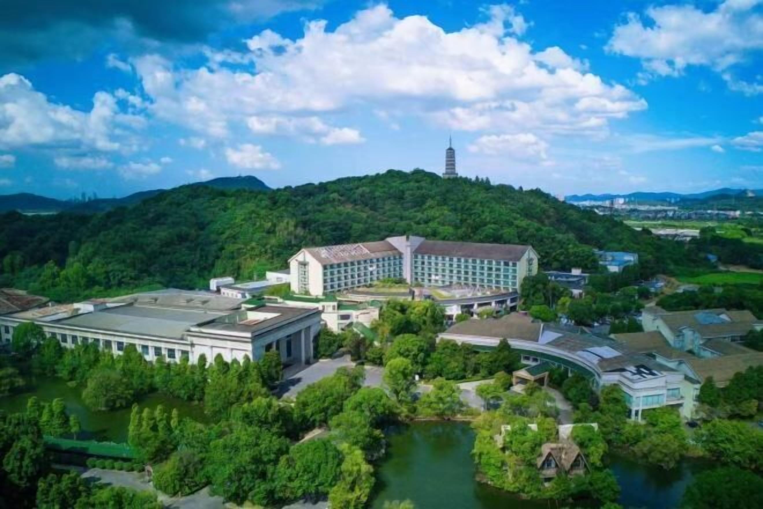 A large hotel complex with multiple buildings, surrounded by lush greenery and a river.