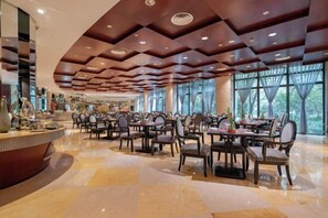 Un restaurante espacioso con un diseño moderno de techo y ventanas amplias que ofrecen vistas al exterior.
