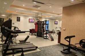 A gym with cardio machines, weightlifting equipment, and a television screen. - Taixuhu Holiday Hotel (Hangzhou)