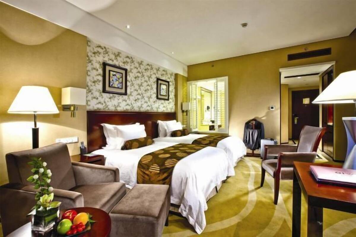Une chambre d’hôtel avec un grand lit, deux tables de chevet, un bureau, une chaise et un canapé.