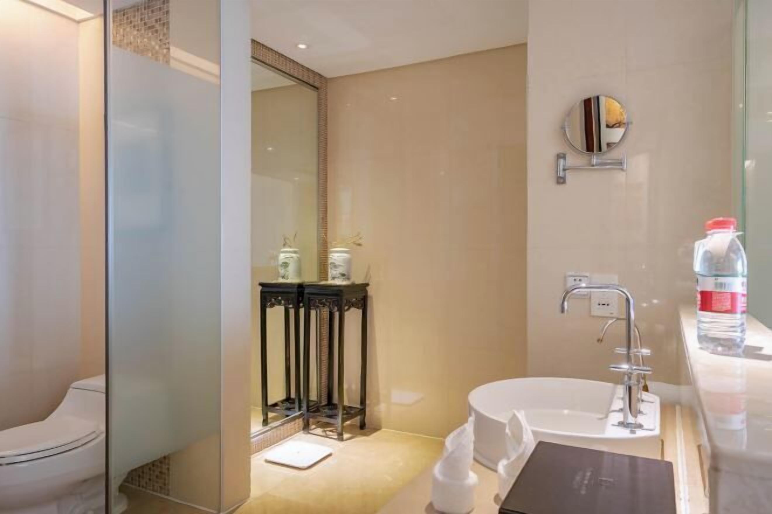 Une salle de bain moderne avec une douche à parois de verre, un lavabo blanc et un miroir doté d’un cadre décoratif.