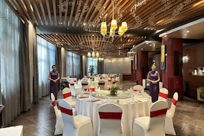 A banquet hall with round tables, white chairs, and red sashes, featuring a wooden ceiling and chandeliers. - Taixuhu Holiday Hotel (Hangzhou)