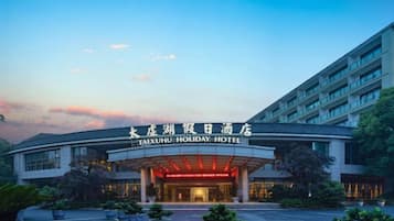 Exterior del Hotel Taixihu Holiday, con cielo despejado y entrada bien iluminada.