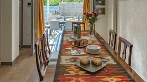 A dining area with a long table set for a meal, featuring a variety of desserts and a vase of flowers.