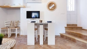 Uma cozinha moderna com uma ilha central, armários brancos e uma televisão de tela plana.