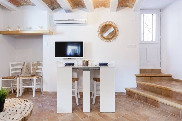 A modern kitchen with a central island, white cabinetry, and a flat-screen TV.