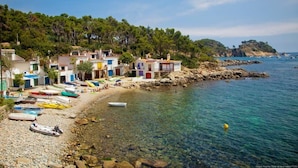 Uma vila costeira com edifícios coloridos, uma praia de pedras e barcos.