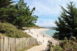 A beach with a wooden walkway leading to the shore, surrounded by pine trees. - Vacation rentals in Beg-Meil 6 people (Fouesnant)