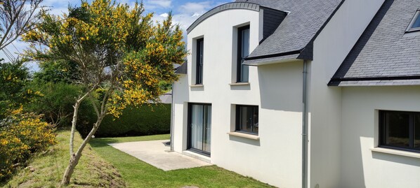 A modern two-story house with a curved roof, large windows, and a well-maintained lawn. - Vacation rentals in Beg-Meil 6 people (Fouesnant)