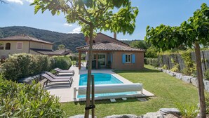 Une villa dotée d’une piscine, d’un patio couvert et offrant une vue sur les collines environnantes.
