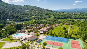 Un quartier résidentiel avec des villas, une piscine et des courts de tennis.