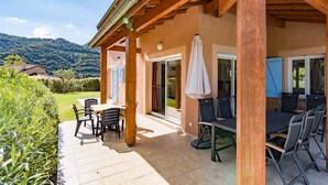 Un patio couvert avec des sièges d’extérieur, une vue sur les montagnes et un jardin bien entretenu.