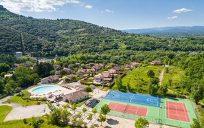 Un quartier résidentiel avec des villas, une piscine et des courts de tennis.