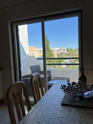 Enjoy a serene view of the surrounding landscape from this balcony, featuring a table for dining and a comfortable seating area.