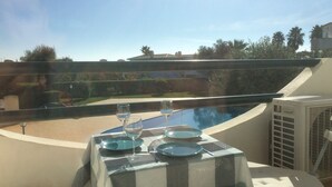 Mesa posta para dois com vista para uma piscina e vegetação ao redor.