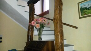 A staircase with a wooden handrail, a vase with pink flowers, and a painting on the wall.