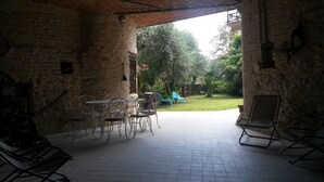 An outdoor patio with a brick wall, a table with four chairs, and a blue plastic chair.
