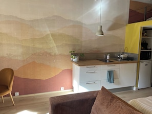 Een moderne keuken met een houten aanrecht, witte kasten en een geel accentmuur.