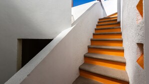 Una escalera con peldaños anaranjados y paredes blancas, que conduce a un nivel superior.