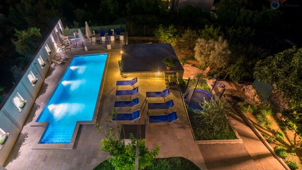 A rectangular swimming pool with a tiled deck, surrounded by lounge chairs and a covered seating area. - Spacious villa with an outdoor swimming pool (Ðuraševici)