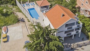 An aerial view of a residential area with a swimming pool, houses with red-tiled roofs, and a view of the sea. - Spacious villa with an outdoor swimming pool (Ðuraševici)