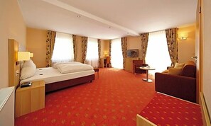 A hotel room with a bed, a sofa, a desk, and a television. - Weinberghotel Nalbach (Reil)