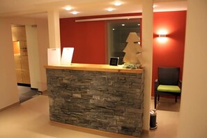 A reception desk with a stone facade, a chair, and a lamp. - Weinberghotel Nalbach (Reil)