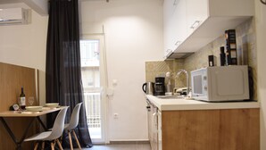 Une cuisine compacte avec un coin repas, comprenant une table avec des chaises, un four à micro-ondes et une machine à café.