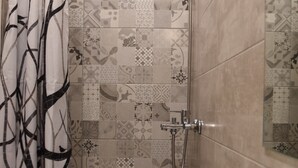 Une salle de bain avec une douche, un lavabo et un miroir.
