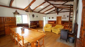 A rustic kitchen with wooden furniture, a dining table, and a chimney.