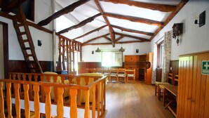 A room with wooden beams, a wooden railing, and a wooden table with chairs.