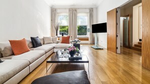 Een moderne woonkamer met een modulaire bank, een glazen salontafel en een flatscreen televisie.