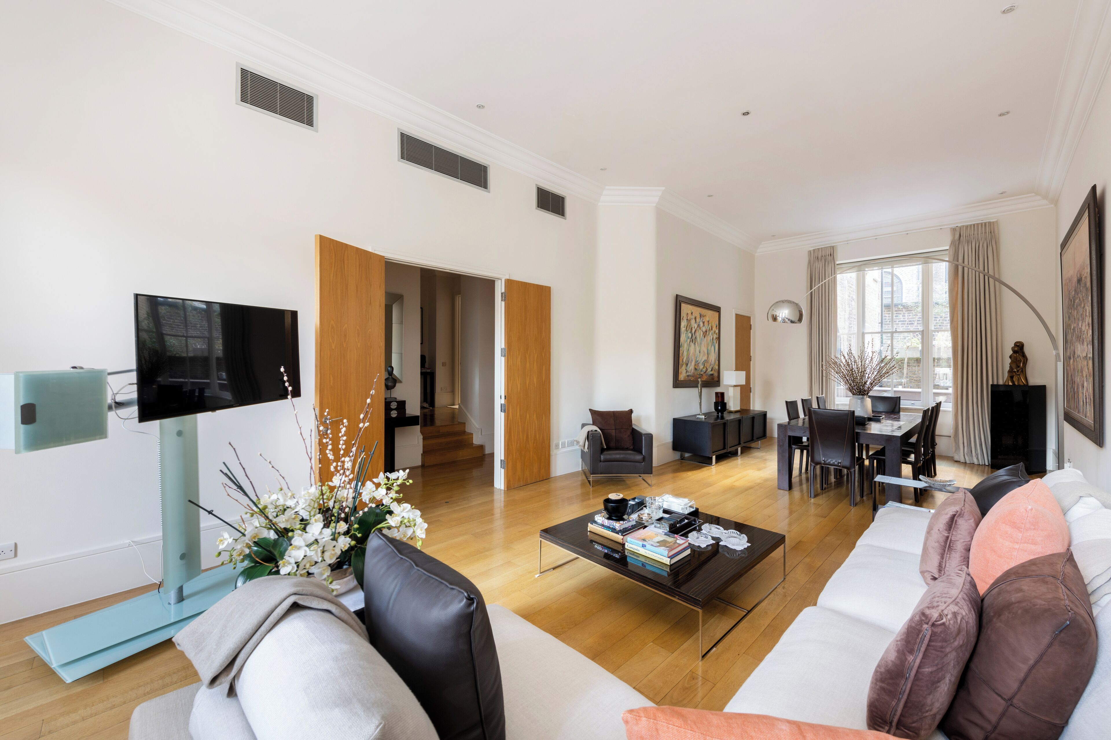 Un salon moderne comprenant un canapé, une table basse, un téléviseur et un coin repas avec des chaises et une table.