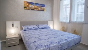 A bedroom with a bed, nightstands, and a wall-mounted painting.