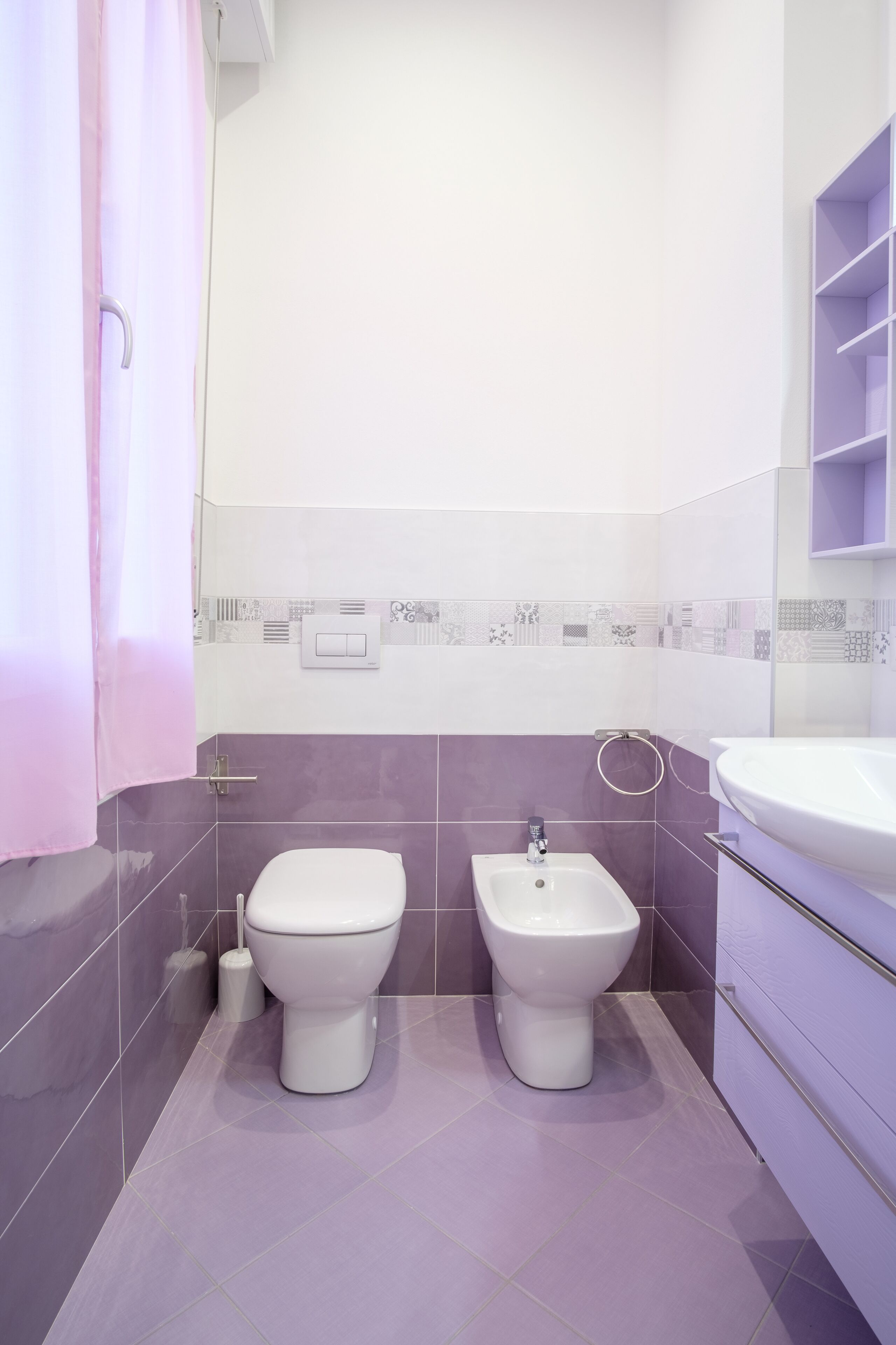 Een badkamer met twee toiletten, een toiletbrons, een wastafel en een douchegordijn.