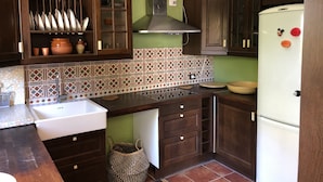 A kitchen with dark wooden cabinets, a white refrigerator, and a patterned tile backsplash. - Villa with views to the sea and the Teide and the Island of La Palma  (Tenerife)