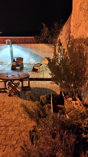 An outdoor seating area with a table and chairs, a lantern, and a wooden structure. - CASA DAMÉLIA POLO2-House near Óbidos in the slope of recycling décor (Vau Óbidos)