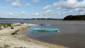 Two boats on a calm river with a sandy shore and distant trees. - CASA DAMÉLIA POLO2-House near Óbidos in the slope of recycling décor (Vau Óbidos)