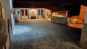 A cobblestone courtyard with a patio area, a dining table, and a hanging lantern. - CASA DAMÉLIA POLO2-House near Óbidos in the slope of recycling décor (Vau Óbidos)