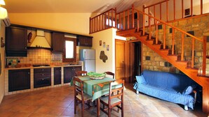 Une cuisine équipée d’une table à manger, de chaises et d’un escalier menant à un niveau inférieur.