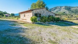 A stone house with a tiled roof, surrounded by a gravel driveway and a small garden with bushes. - VILVAL Finca for 4 with pool in Moscari (Moscari)