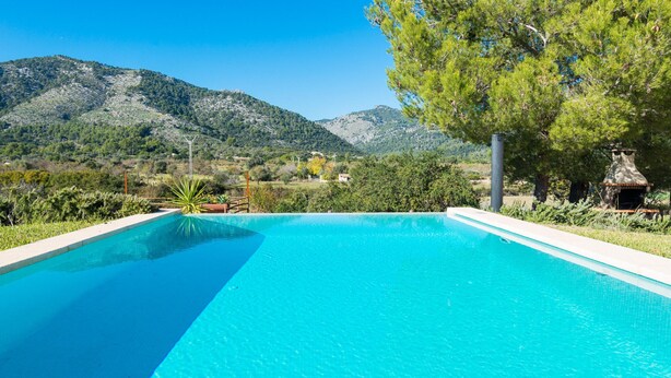 A rectangular swimming pool with clear blue water, surrounded by greenery and a mountainous landscape in the background. - VILVAL Finca for 4 with pool in Moscari (Moscari)