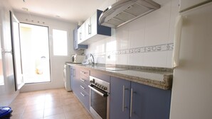Una cocina con horno empotrado, lavamanos y armarios.