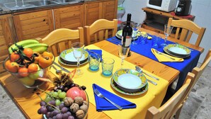 Een eettafel gedekt met borden, glazen en een fles wijn.