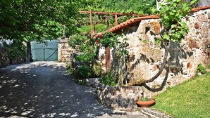 Eine Steinsäule mit einem Blumentopf, einem Metallgitter und einem Steinweg, der zu einem Gebäude führt.